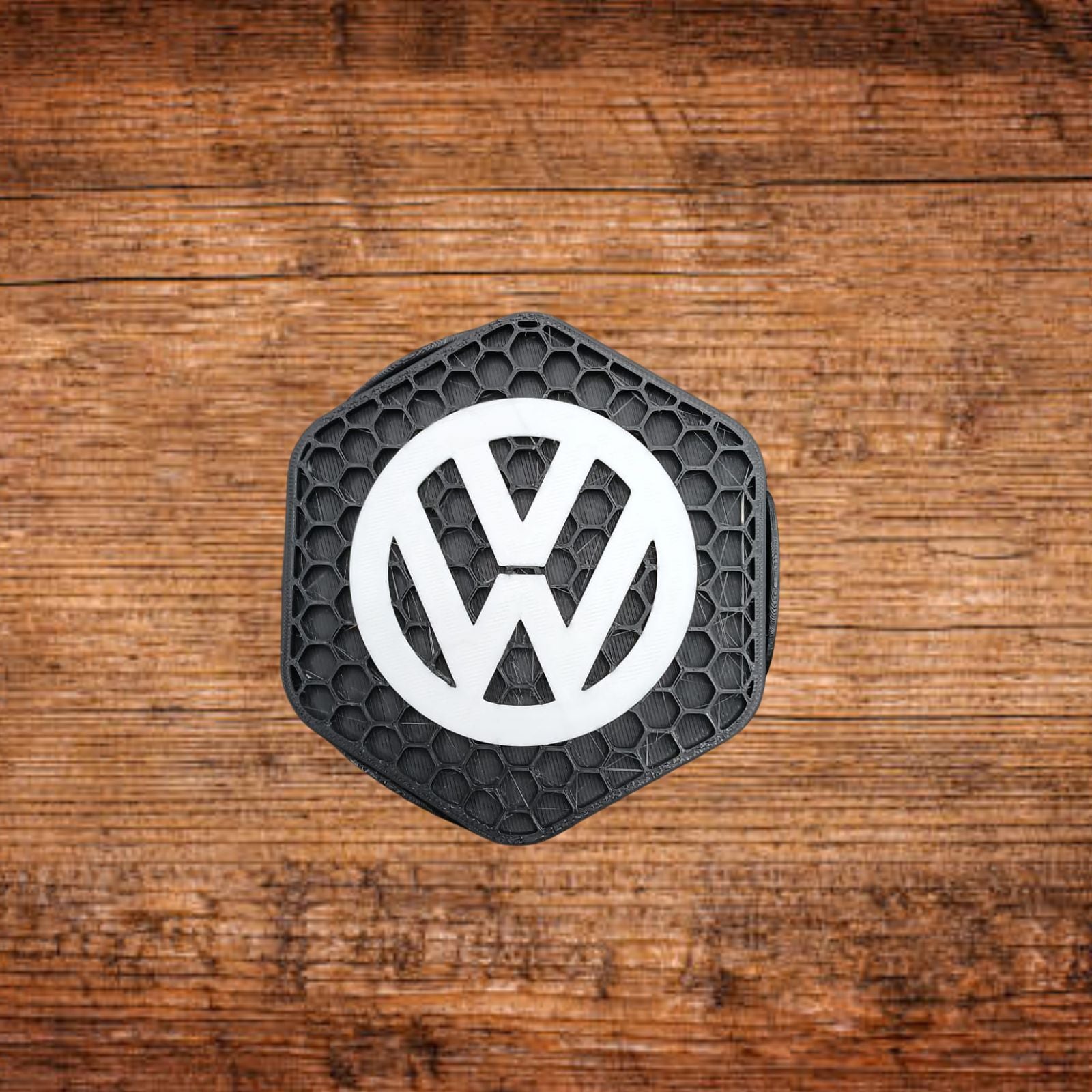 Schwarzer VW-Untersetzer mit weißem VW-Logo, sechseckigem Wabenmuster