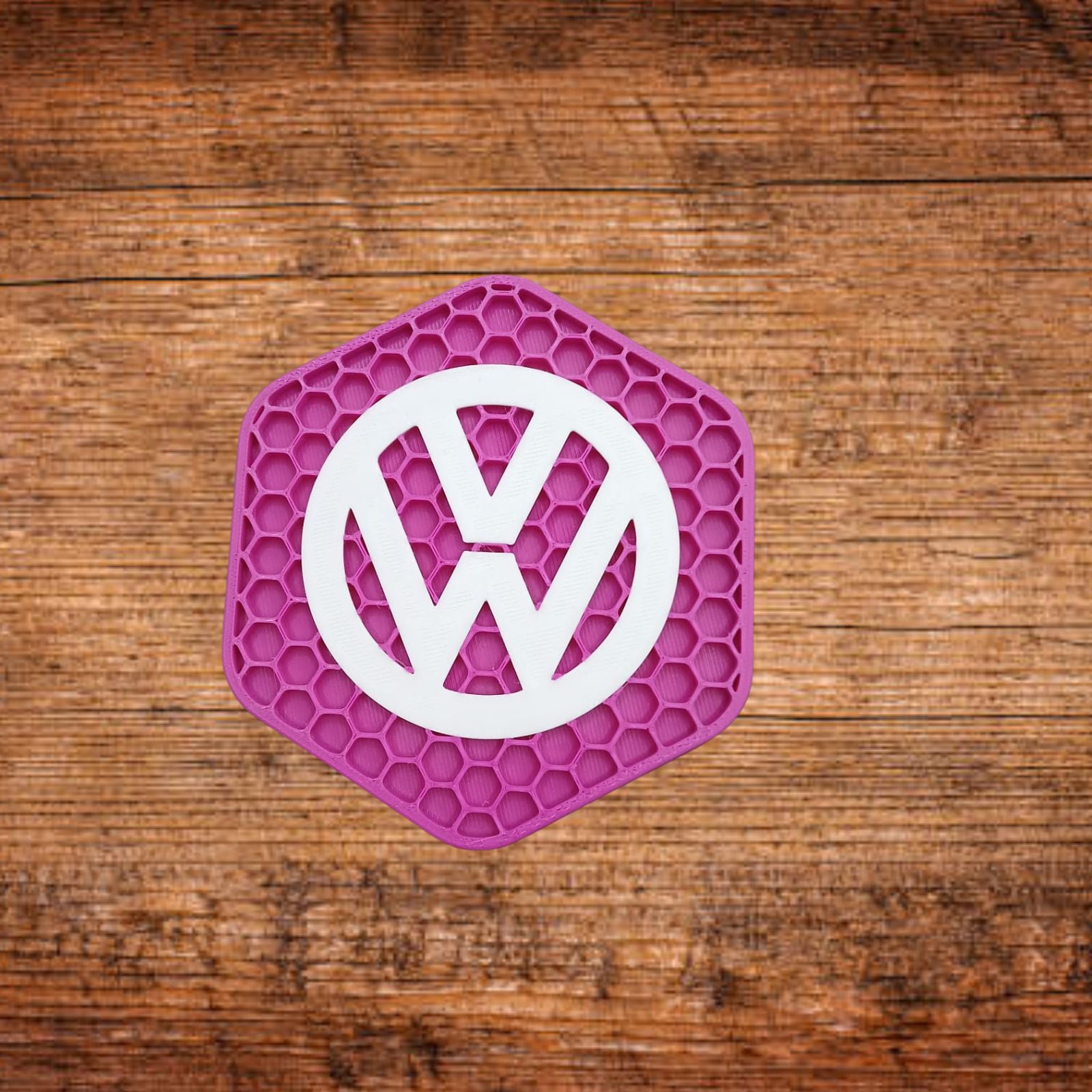 Neon-pinkfarbener VW-Untersetzer mit weißem VW-Logo, sechseckigem Wabenmuster