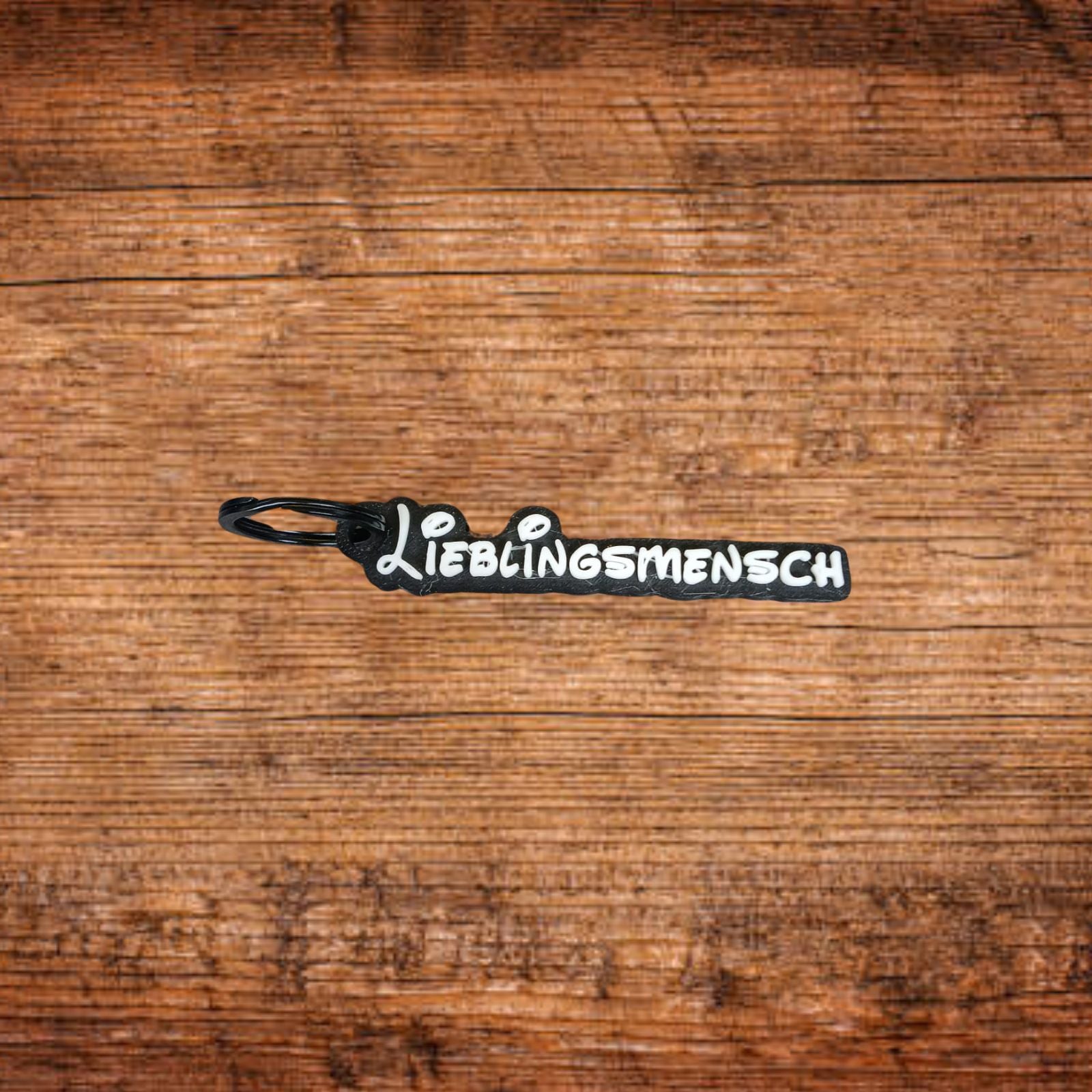 Schlüsselanhänger-Anhänger: schwarzes Etikett mit weißem Schriftzug und Schlaufe.