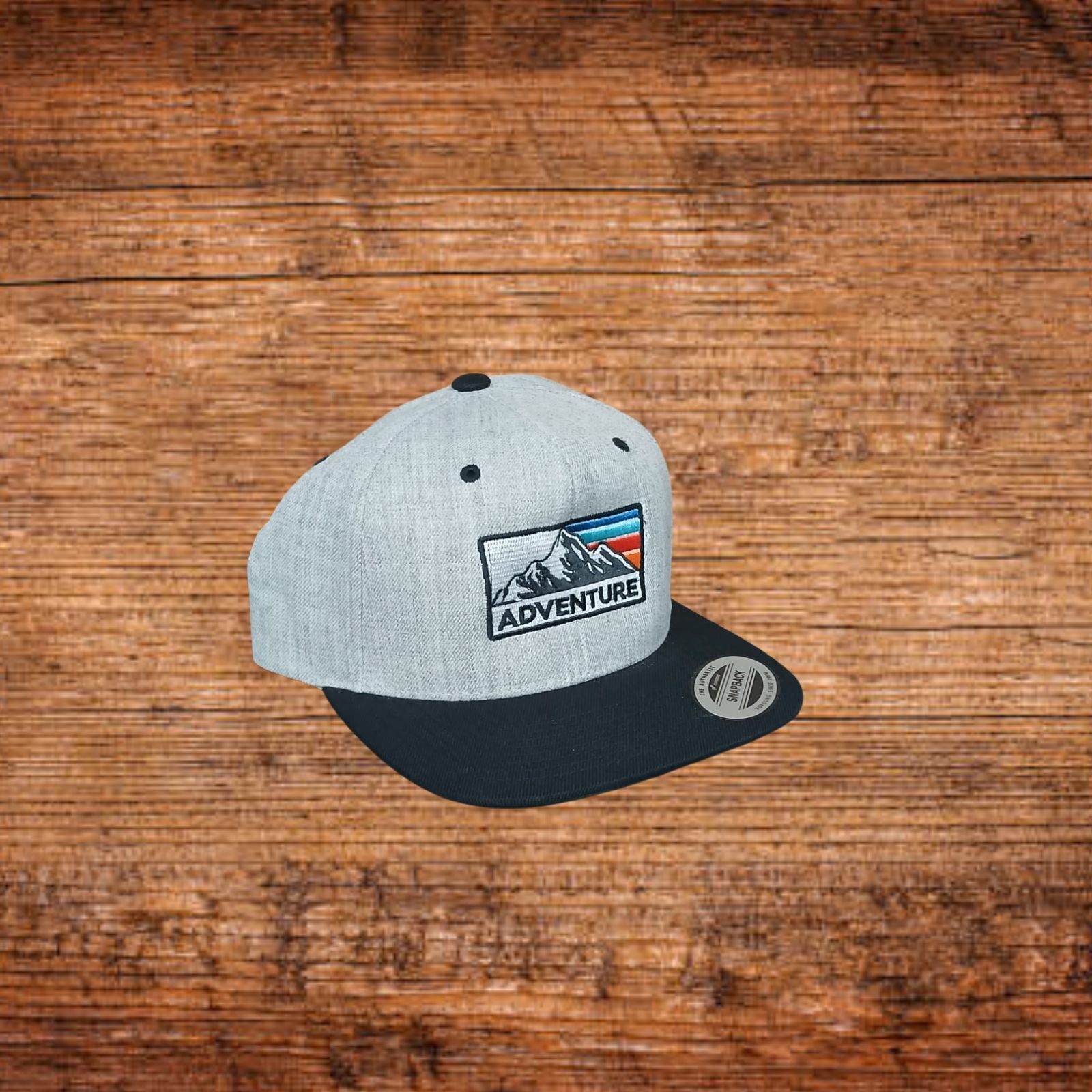Snapback-Kappe mit hellgrauem Oberteil, schwarzem Schirm und Front-Patch mit Berggrafik