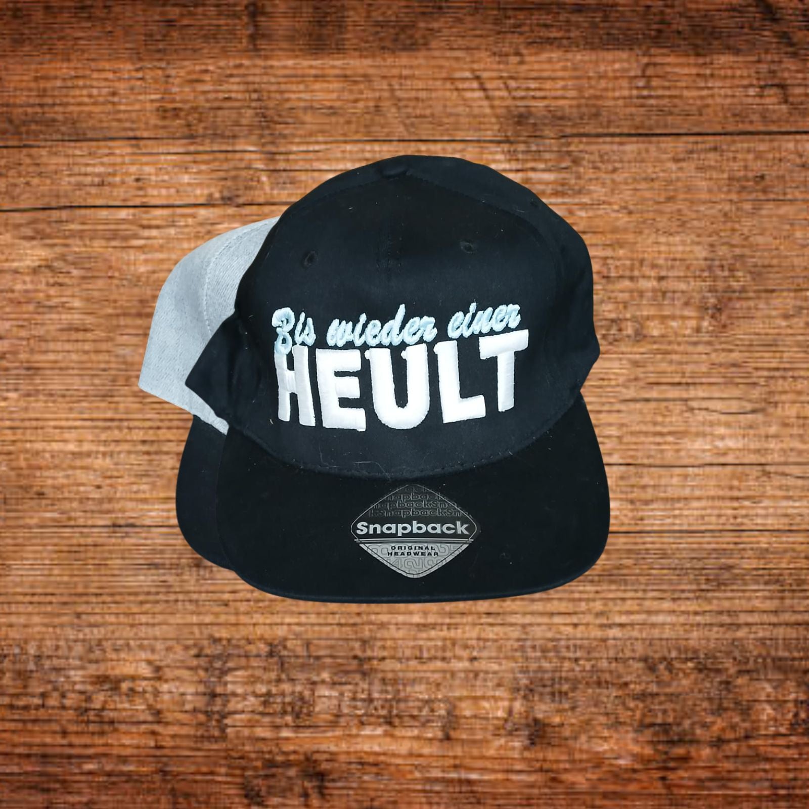 Schwarze Snapback-Kappe mit grau abgesetzten Seiten und großem Schriftprint vorne