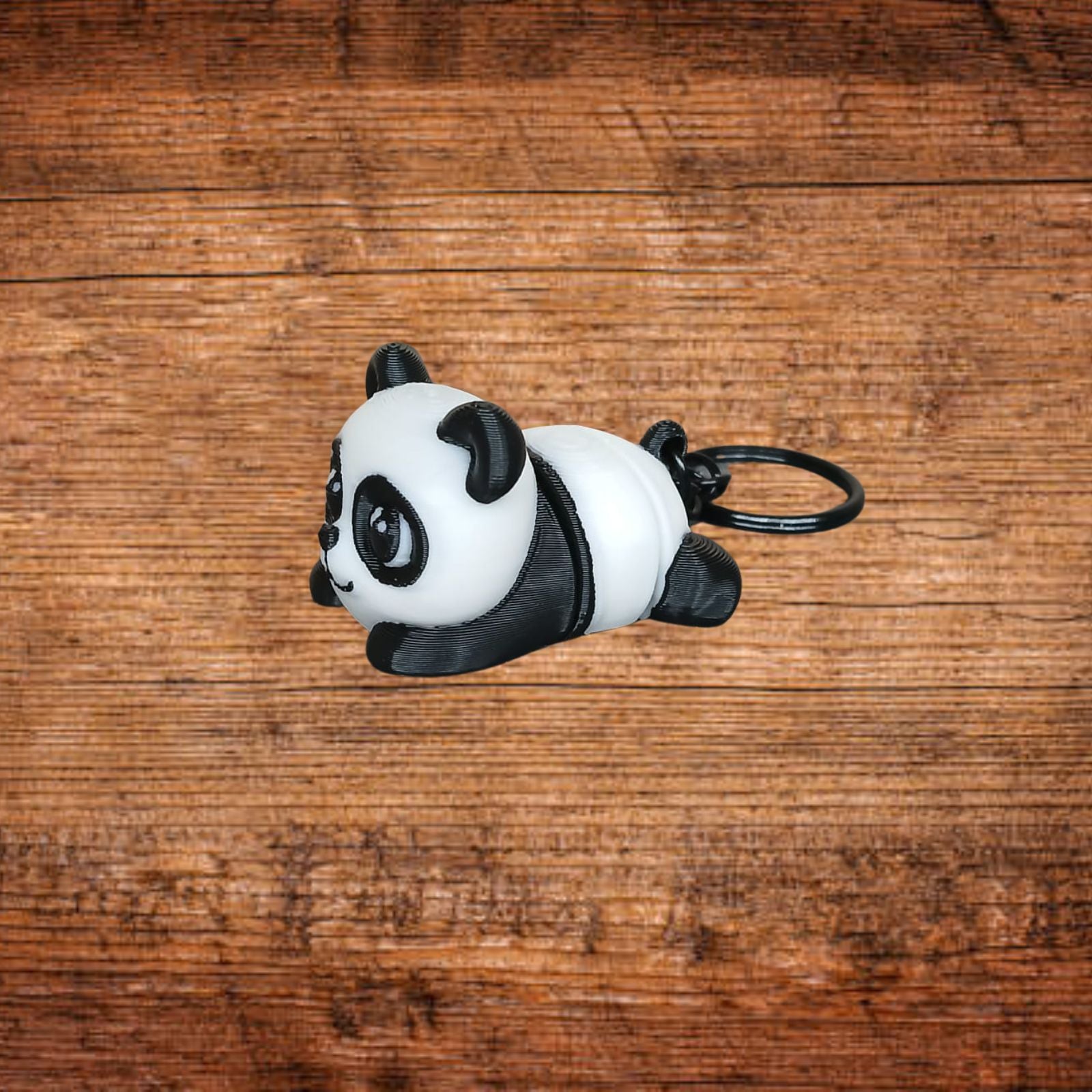 Panda-Schlüsselanhänger, liegendes Stofftier mit schwarzen Ohren und Öse am Ring