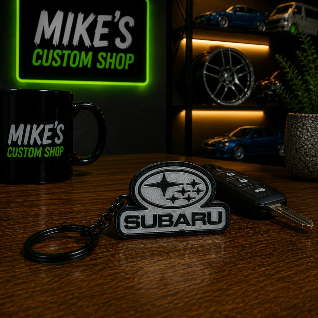 Schlüsselanhänger mit Subaru-Emblem (3D-Druck) in Grau/Schwarz, mit Schlüsselring.