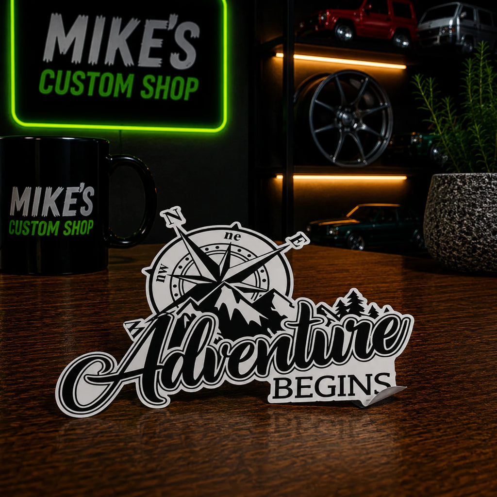 Vinyl-Sticker „Adventure Begins“ mit Kompass und Bergsilhouetten